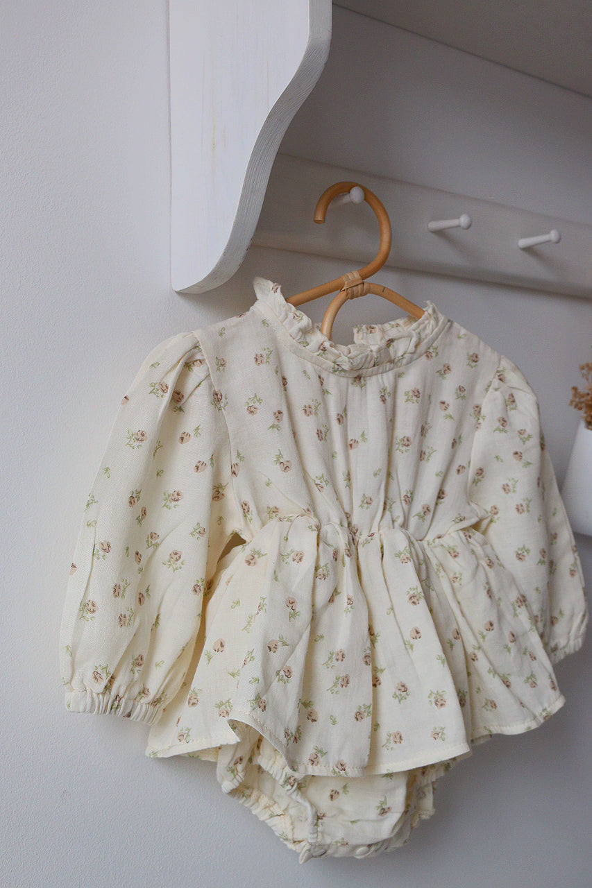 Floral baby outfit hanging on a hook against a white wall