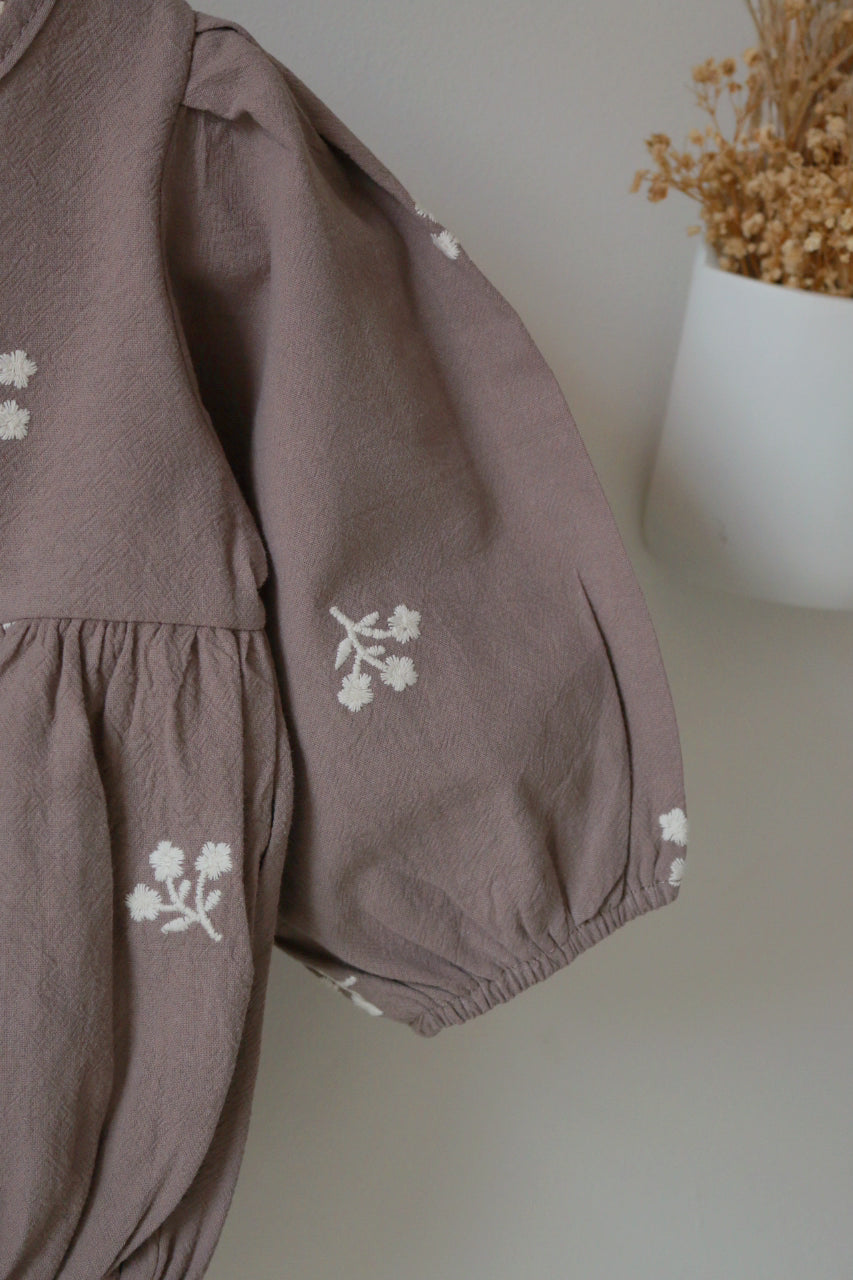 Grey children's outfit with floral embroidery on a neutral background
