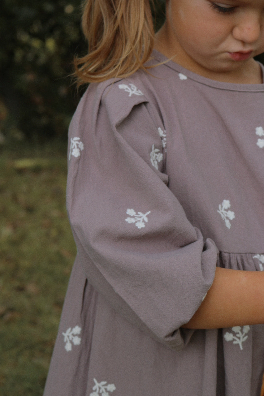 Child wearing a grey dress with floral patterns outdoors