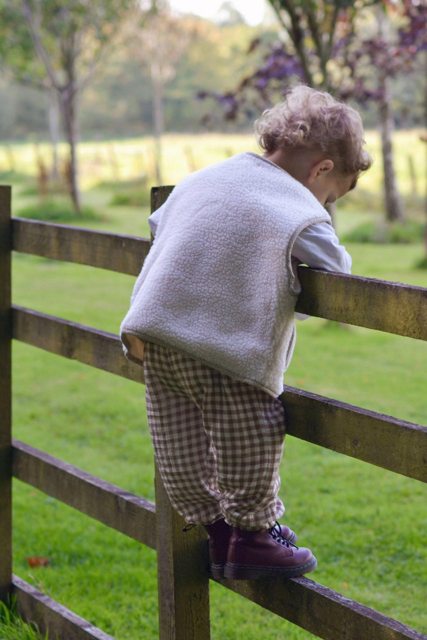 Child sitting on a wooden fence in a park-like setting