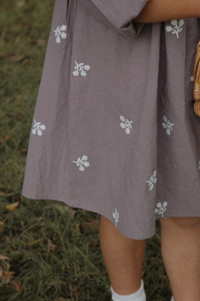 Grey dress with ivory floral patterns worn by a little girl in a natural setting