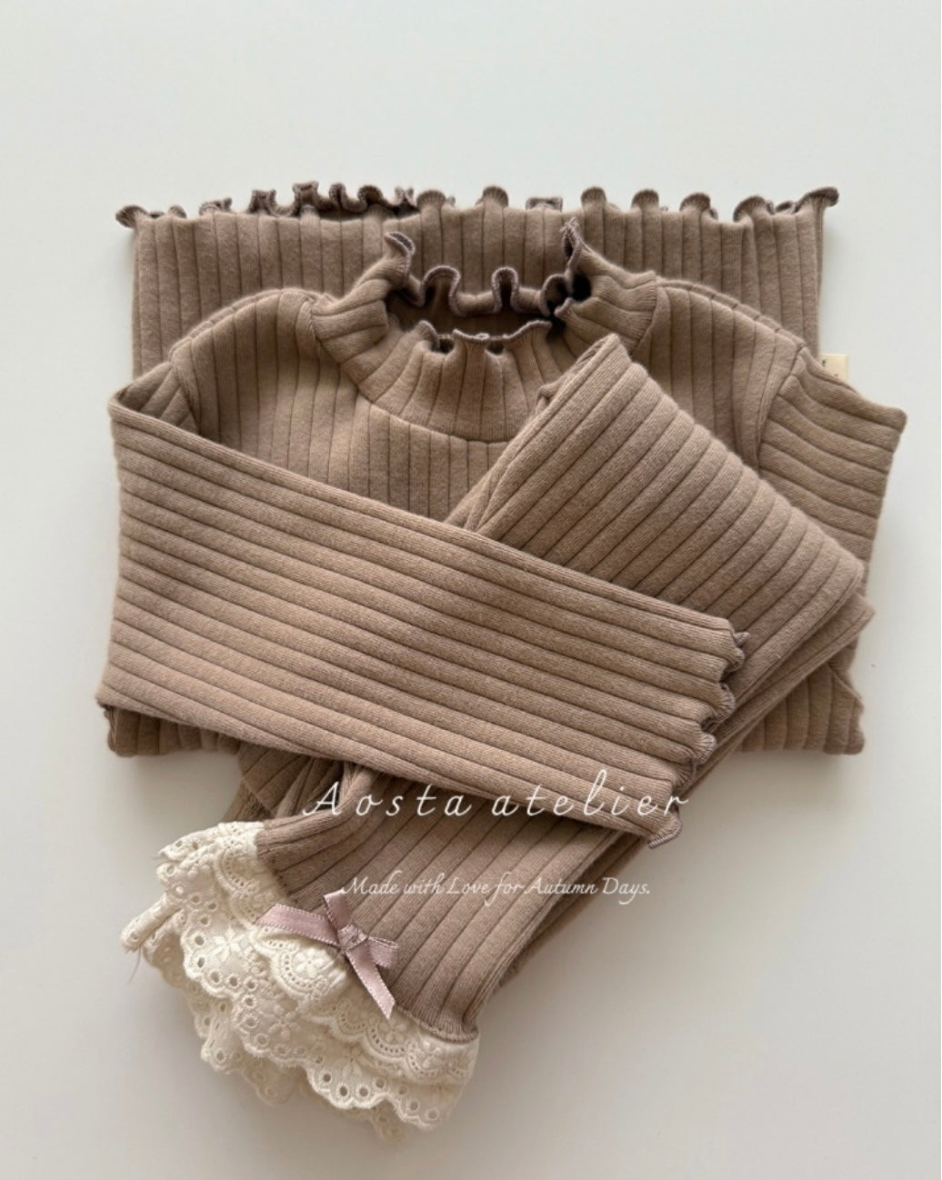 Brown ribbed turtleneck sweater with lace details on a white background, branded 'Aosta atelier'.