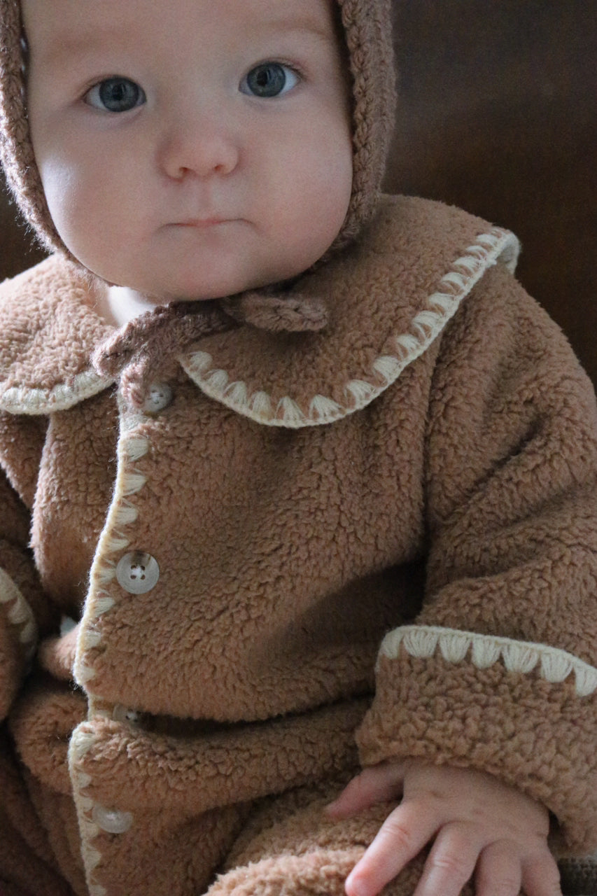 Baby wearing a brown fleece outfit with a hood