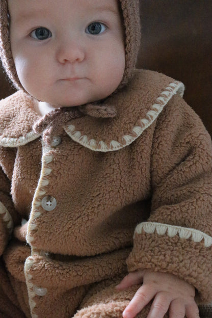 Baby wearing a brown fleece outfit with a hood