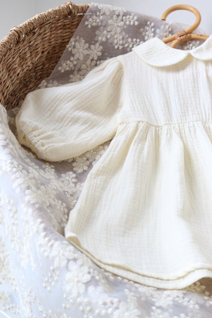 Cream dress draped over a textured surface with a woven basket