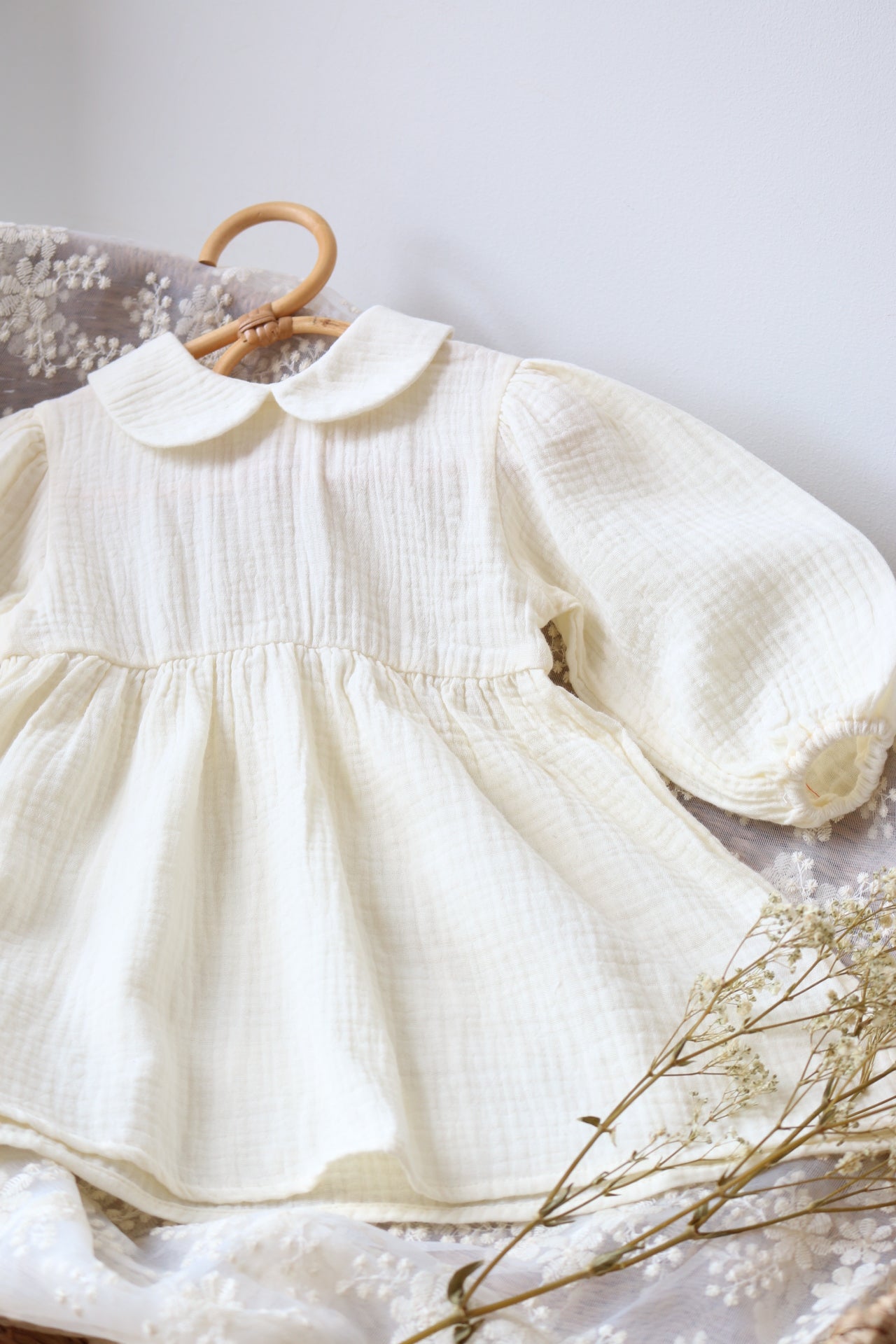 Cream dress with a wooden hanger on a light gray background