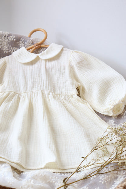 Cream dress with a wooden hanger on a light gray background