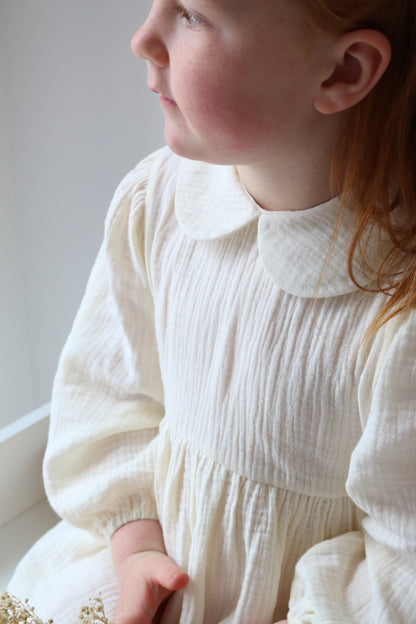 Close-up of a person wearing a white pleated dress with a blurred background