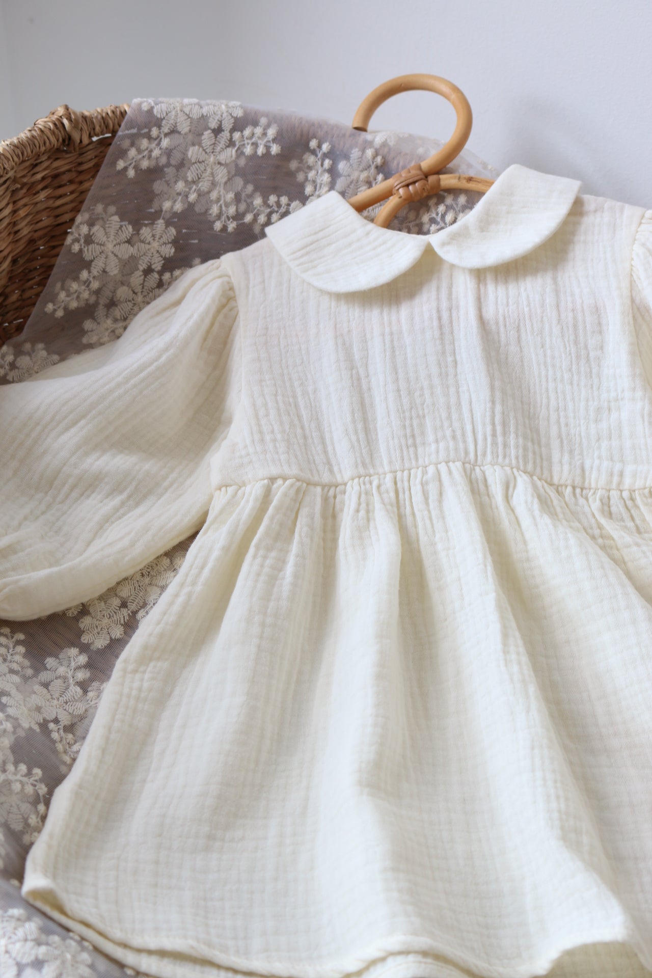 White dress on a wooden hanger with a floral-patterned fabric background