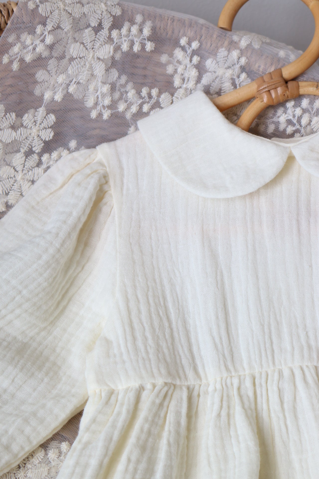 Close-up of a white muslin dress with a floral patterned surface underneath