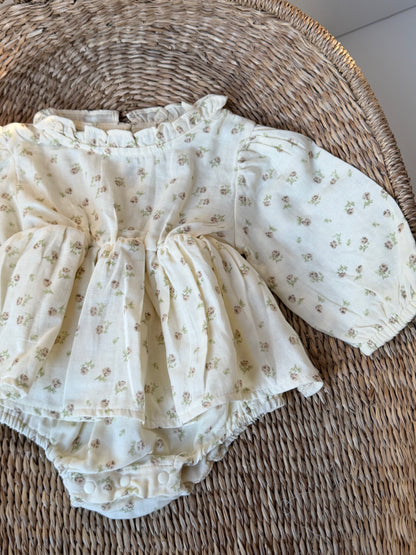 Floral-patterned baby romper on a woven surface