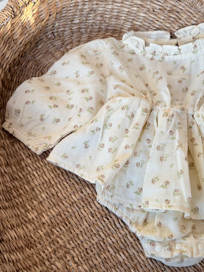 Cream Romper with floral print, flat laid on a wicker basket background.