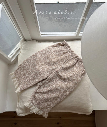 Floral-patterned blanket draped over a cushion on a wooden surface with a window in the background.