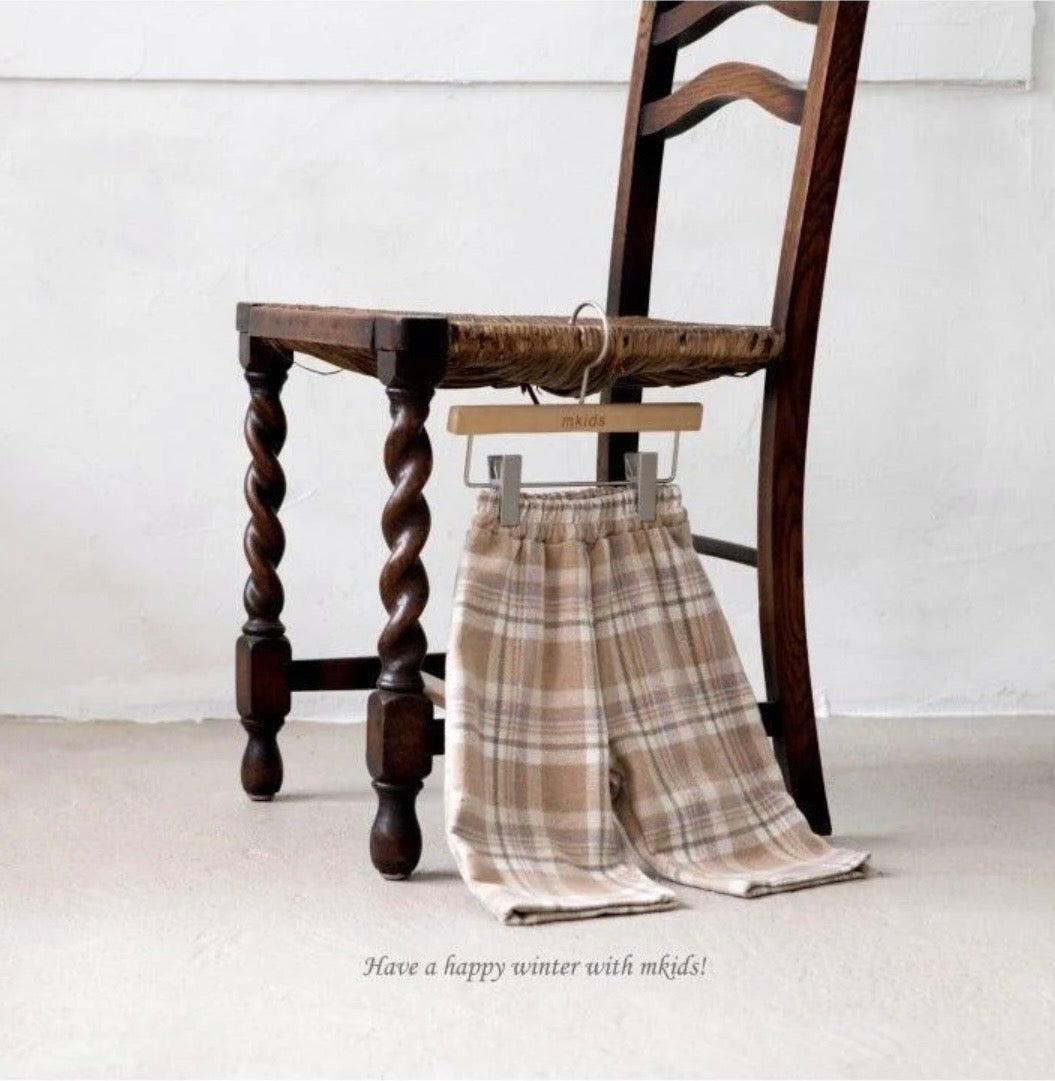 Plaid pants hanging on a wooden chair with a minimal background