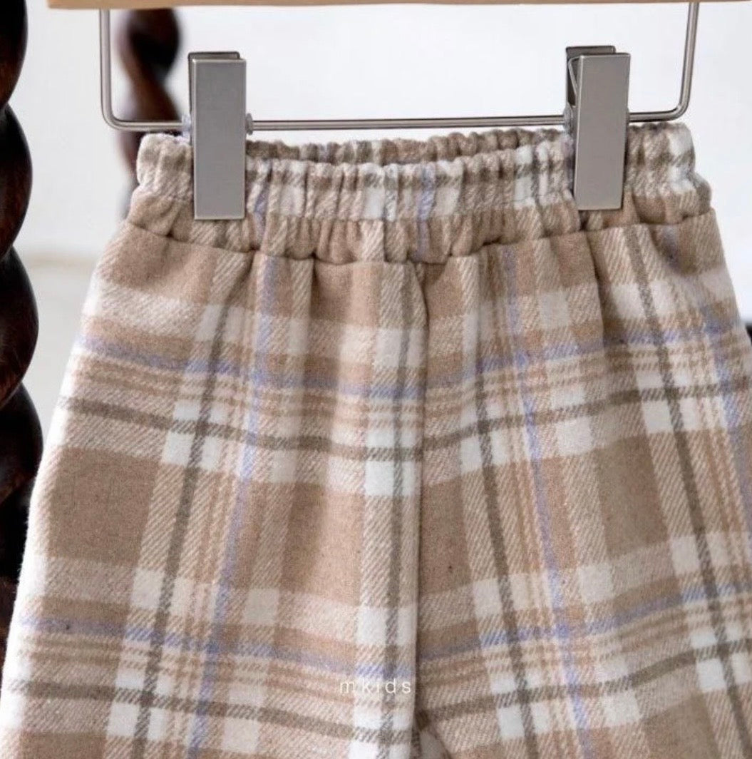 Plaid patterned pants hanging on a rack with a blurred background