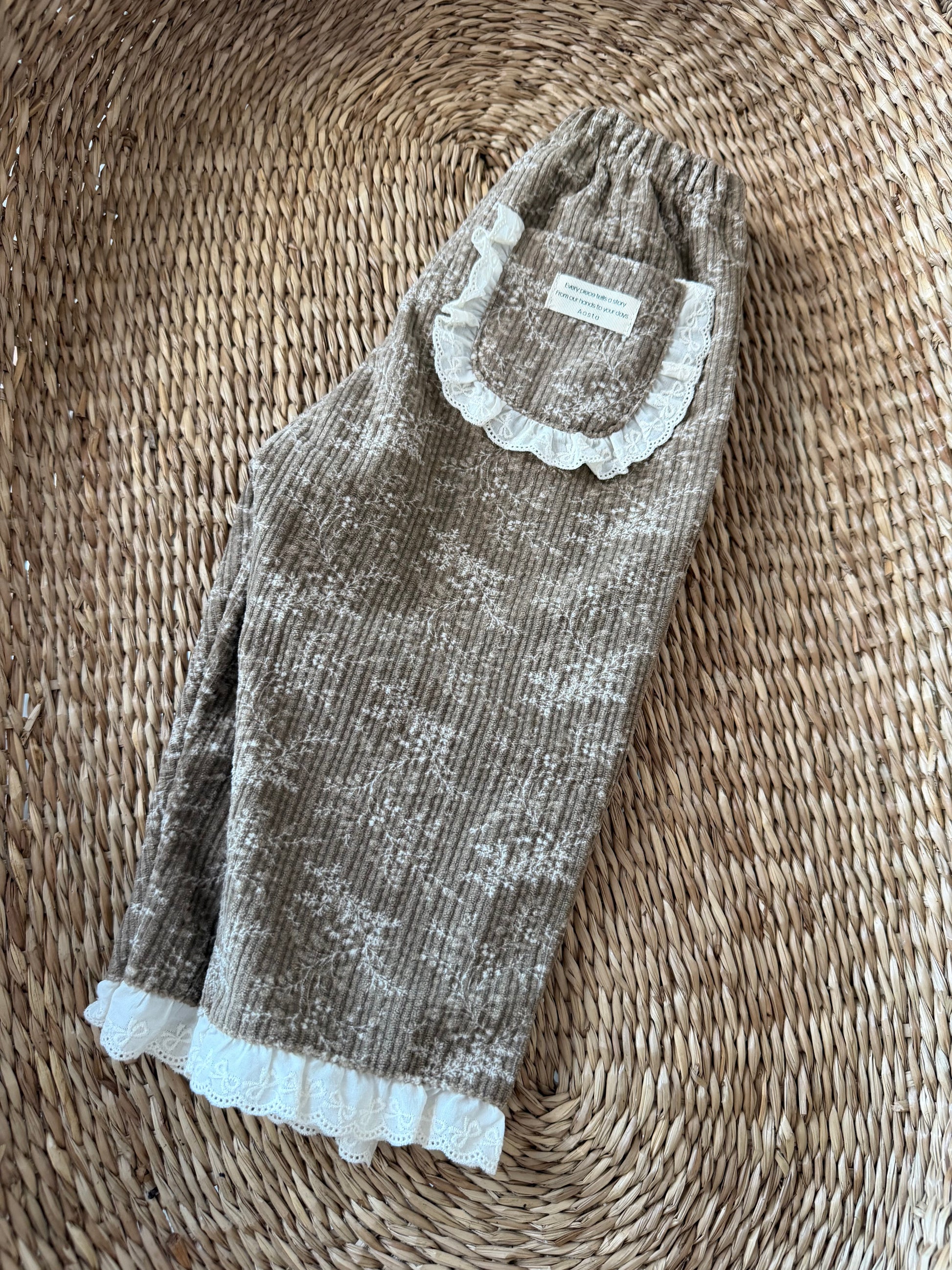 brown ribbed corduroy trousers laid flat on wicker basket 