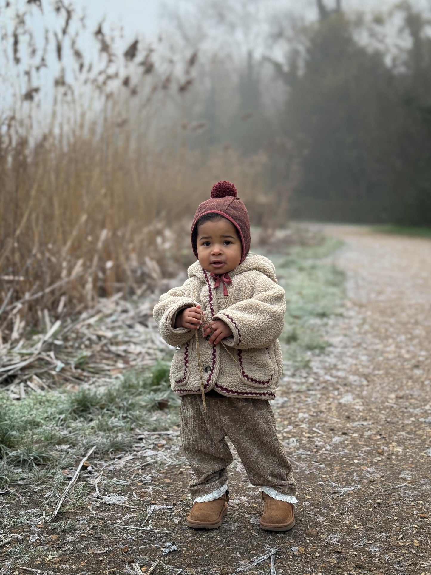 Child in winter clothing standing on a frosty path