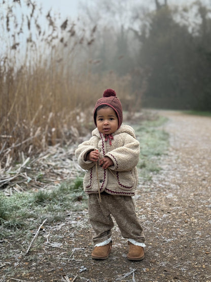 Child in winter clothing standing on a frosty path