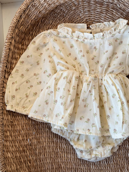 Cream Romper with floral print, flat laid on a wicker basket background.