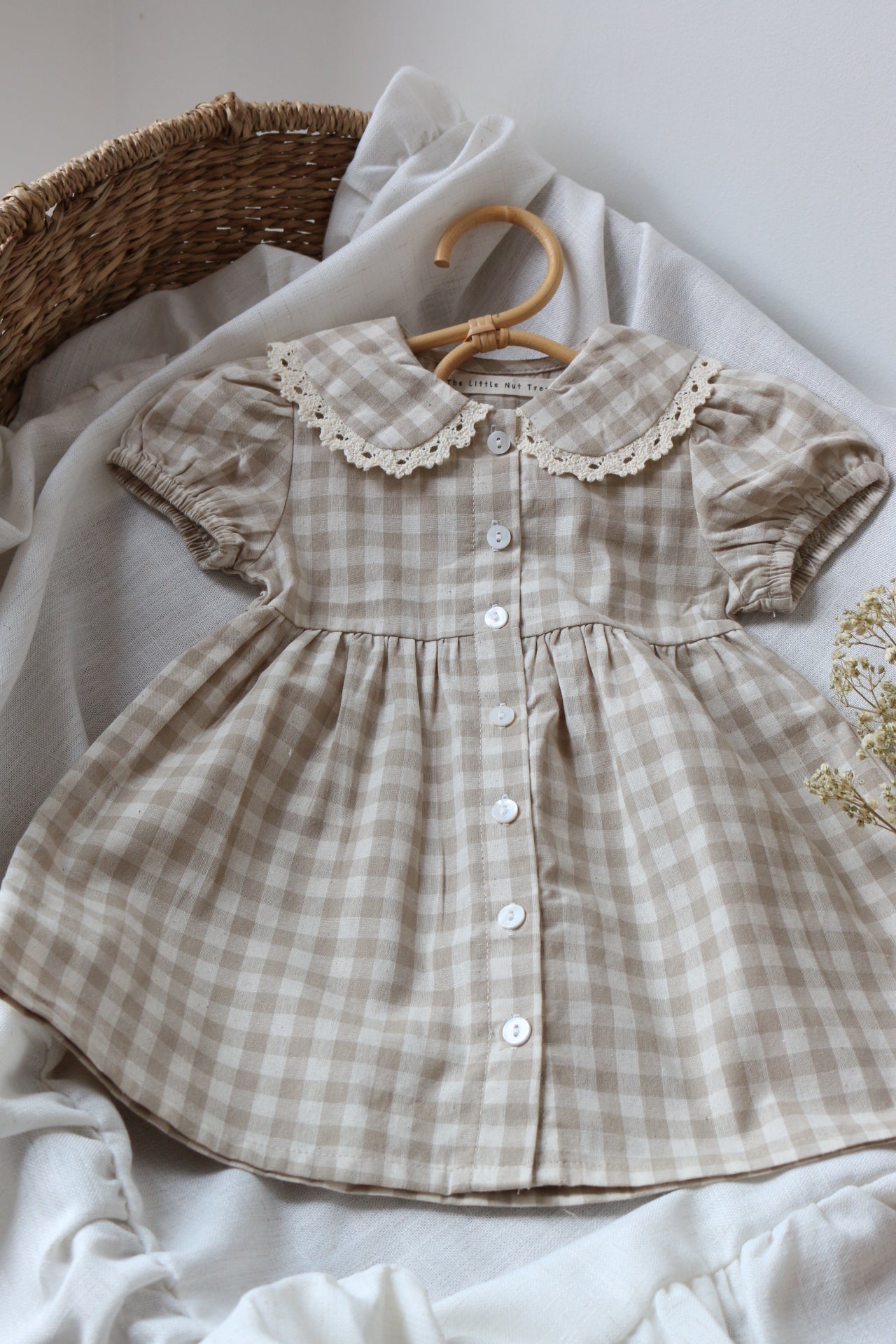 Checkered baby dress with lace trim on a white surface
