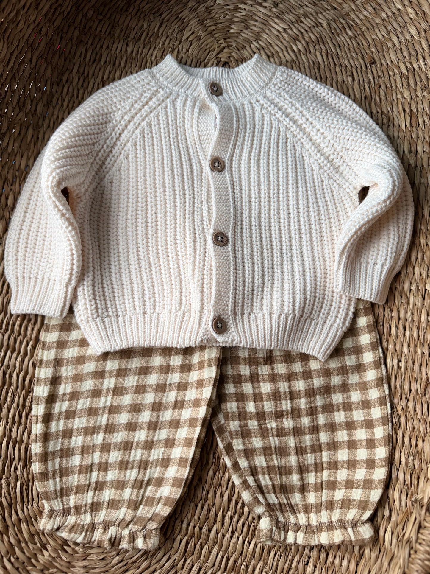 knitted ivory cardigan, gingham pants, outfit flat laid on wicker basket