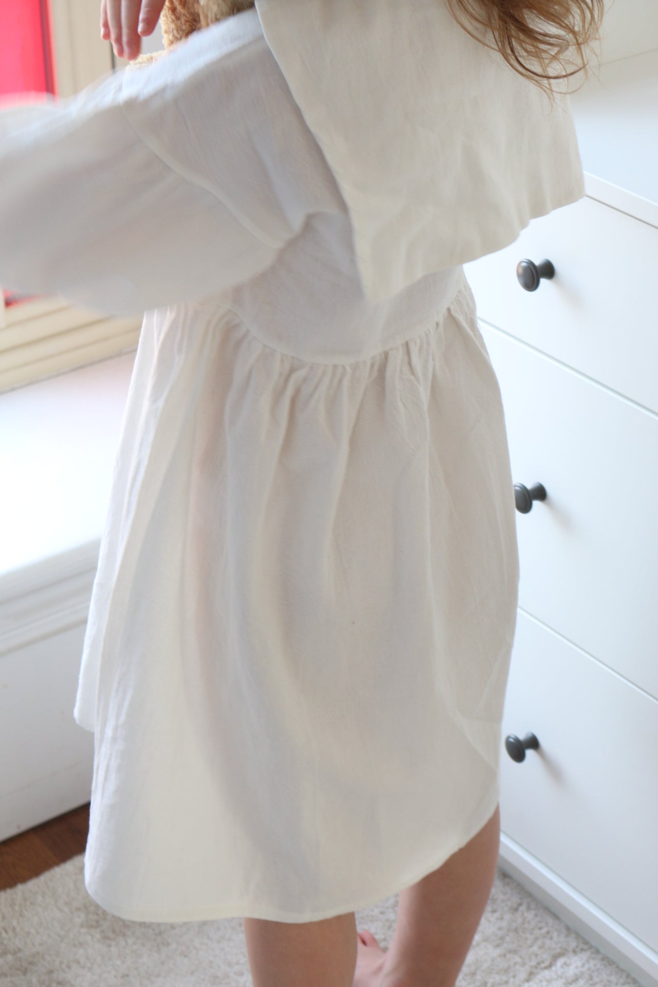 White dress with a fitted bodice and flowing skirt on a person, blurred background
