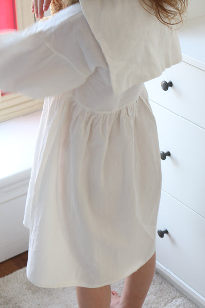 White dress with a fitted bodice and flowing skirt on a person, blurred background