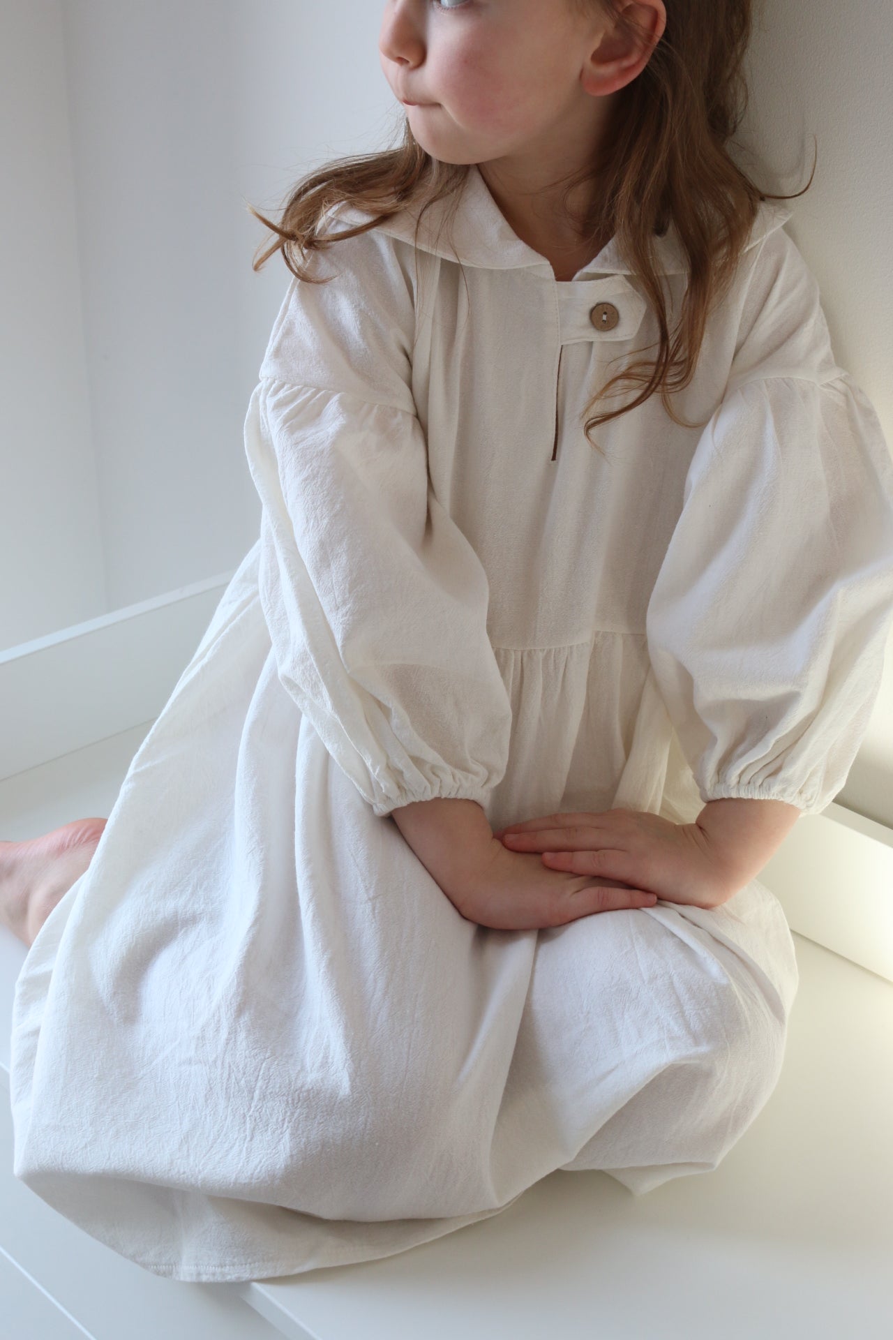 Person wearing a white dress lying on a white surface