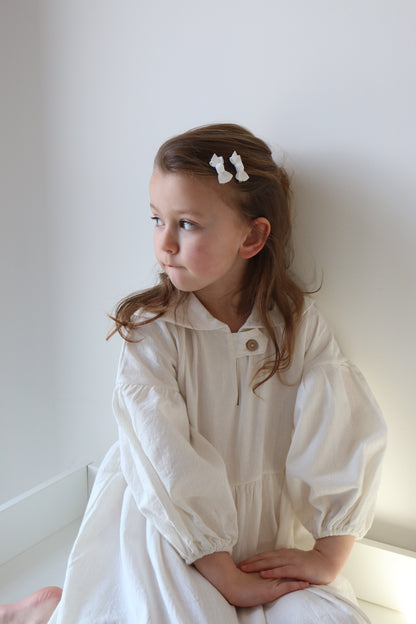 Young girl in a white dress lying on a white surface