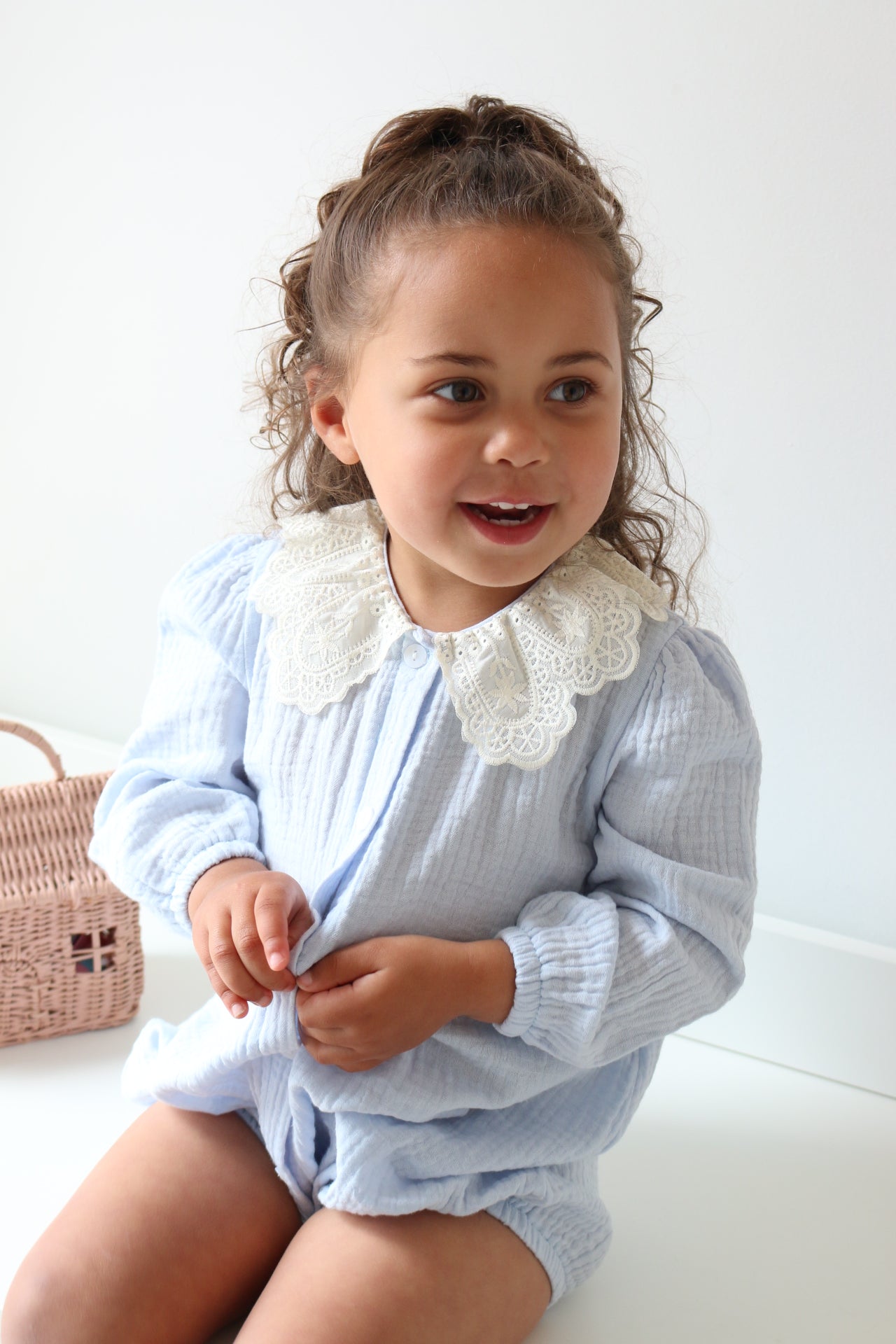 Child wearing a light blue outfit with ruffled details on a white background